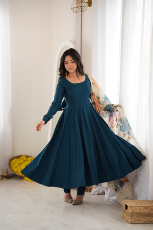 Model twirling in a Peacock Teal Blue Heavy Pure Roman Silk Fully Flared Anarkali Gown Set with Pearl Neckline and Floral Appliqué Organza Dupatta by The Beauty Queen