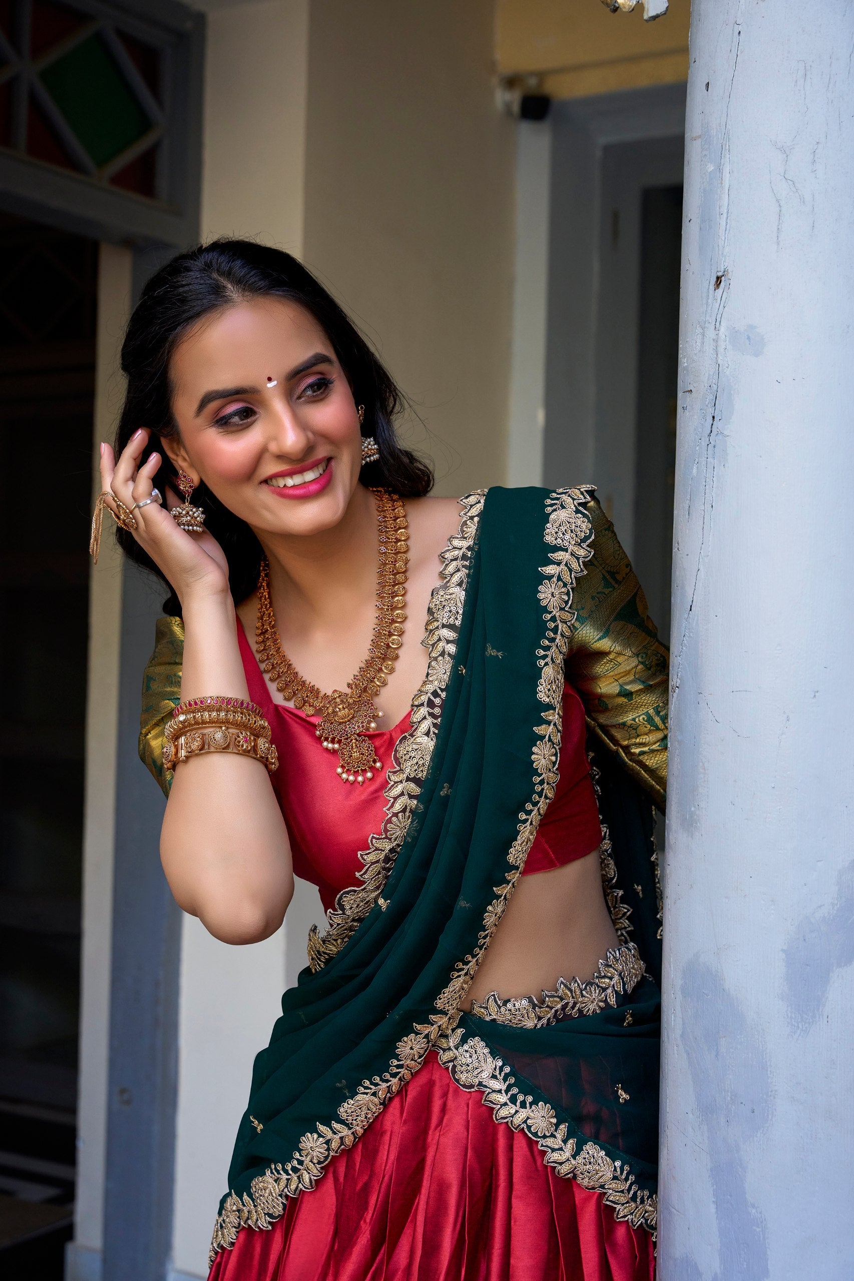 Red South Indian half saree with temple zari border and embroidered green dupatta

