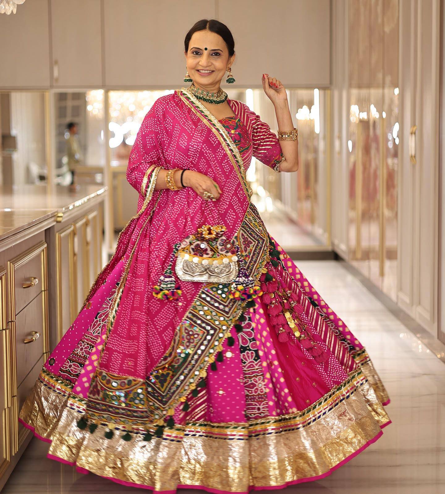 Rani pink heavy muslin cotton Navratri lehenga choli featuring bandhani digital print, real mirror work, hanging tassel latkans, and a broad golden Lampi lace border