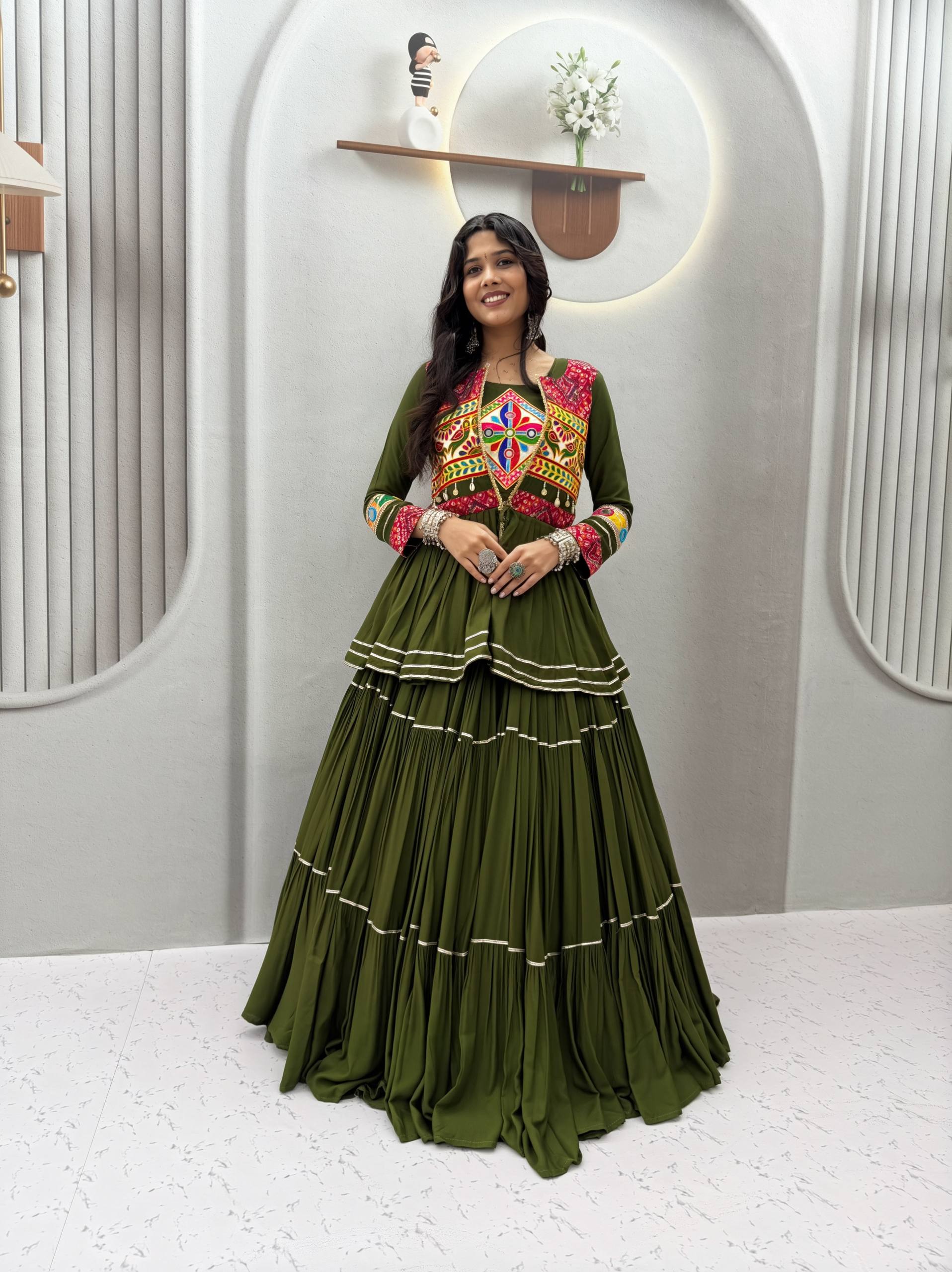 Model Posing Indoors Wearing Dark Olive Green Pure Cotton Heavy Gamthi Work & Mirror Lace With Sikka Lace Navratri Lehenga Choli Set By The Beauty Queen
