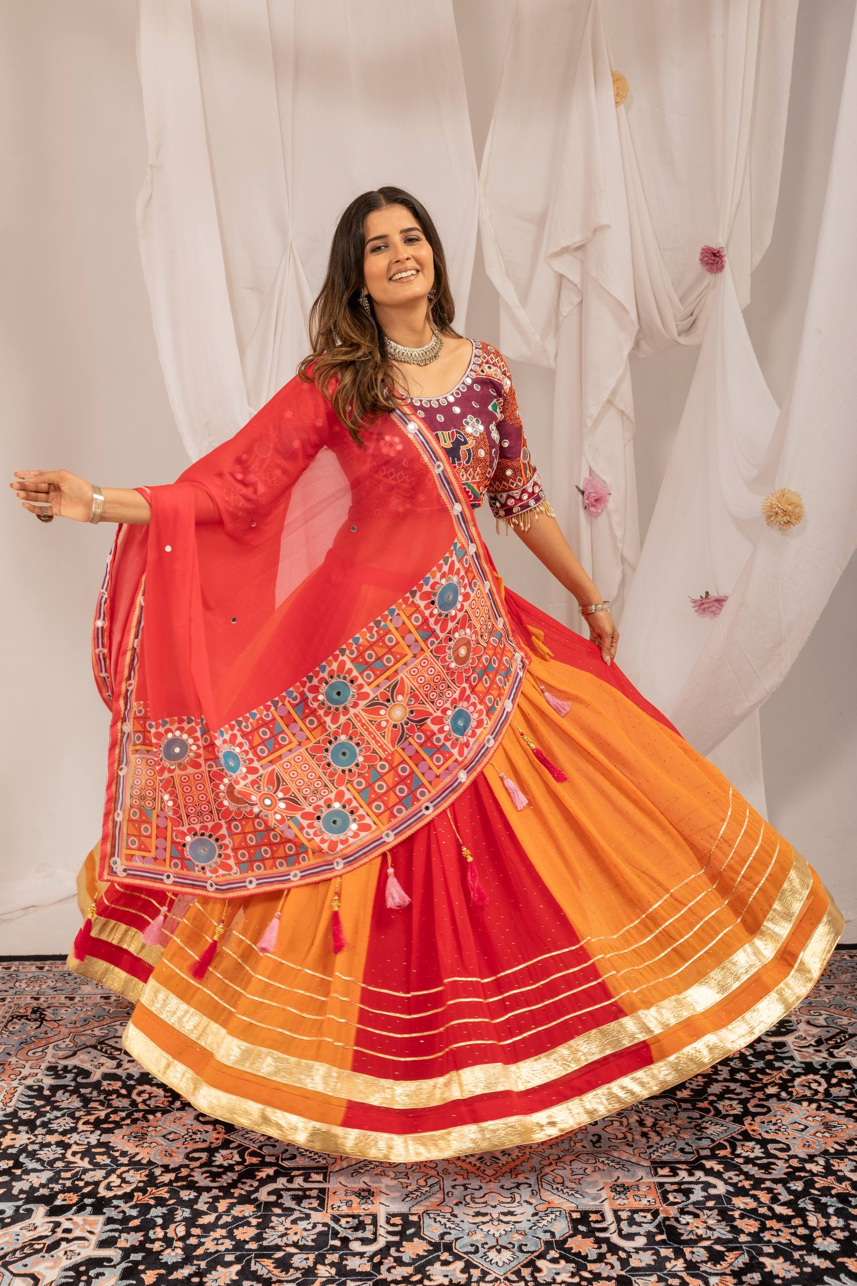 Model Twirling In Multi-Color Orange And Red Faux Georgette Hot Fix Diamond Navratri Lehenga Choli Set By The Beauty Queen