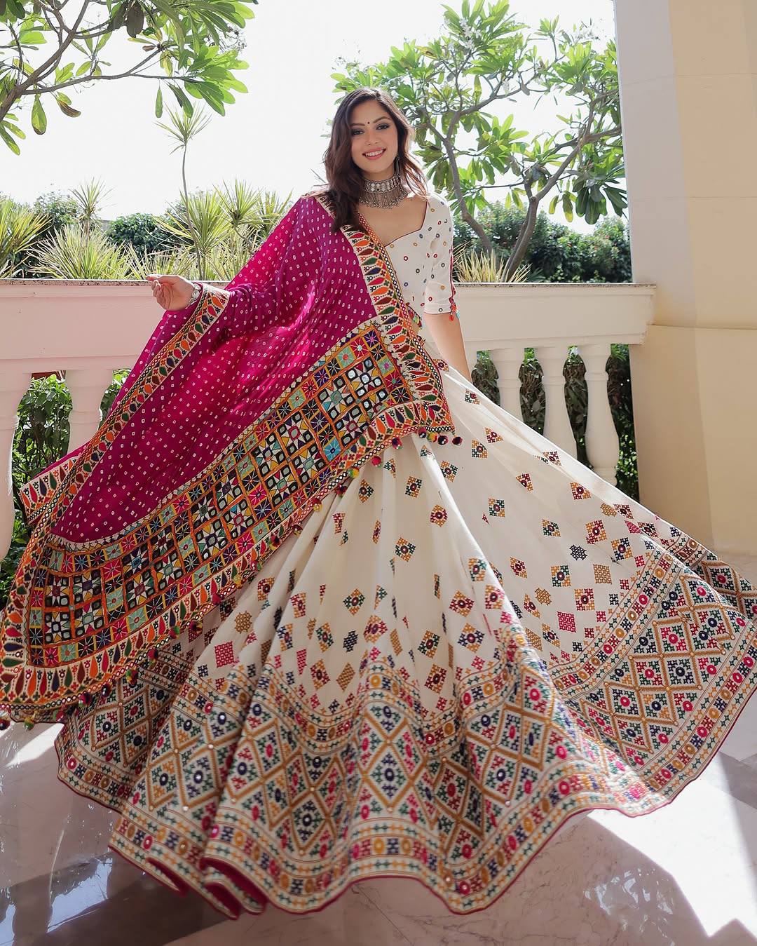 Model Posing Outdoors In Off-White & Multi-Color Heavy Muslin Cotton Beautiful Digital Print & Real Mirror Work Navratri Lehenga Choli Set By The Beauty Queen