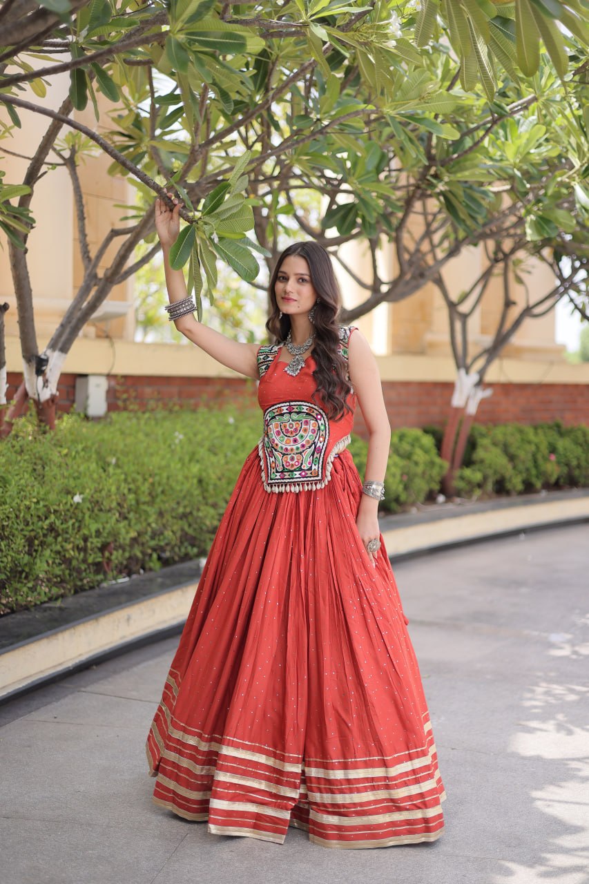 Rust Orange 14kg Rayon Navratri Special Flared Lehenga Choli Set with Sparkling Mukaish (Badla) Work, Multi-Line Gota Patti Borders & Kutchi Embroidered Cowrie Shell Sleeveless Blouse