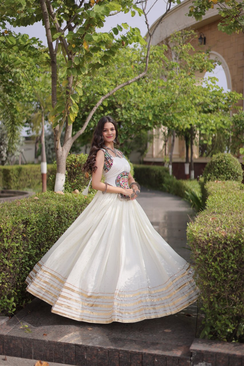 Pristine Off-White Ivory 14kg Rayon Navratri Special Flared Lehenga Choli Set with Sparkling Mukaish (Badla) Work, Multi-Line Gota Patti Borders & Kutchi Embroidered Cowrie Shell Sleeveless Blouse
