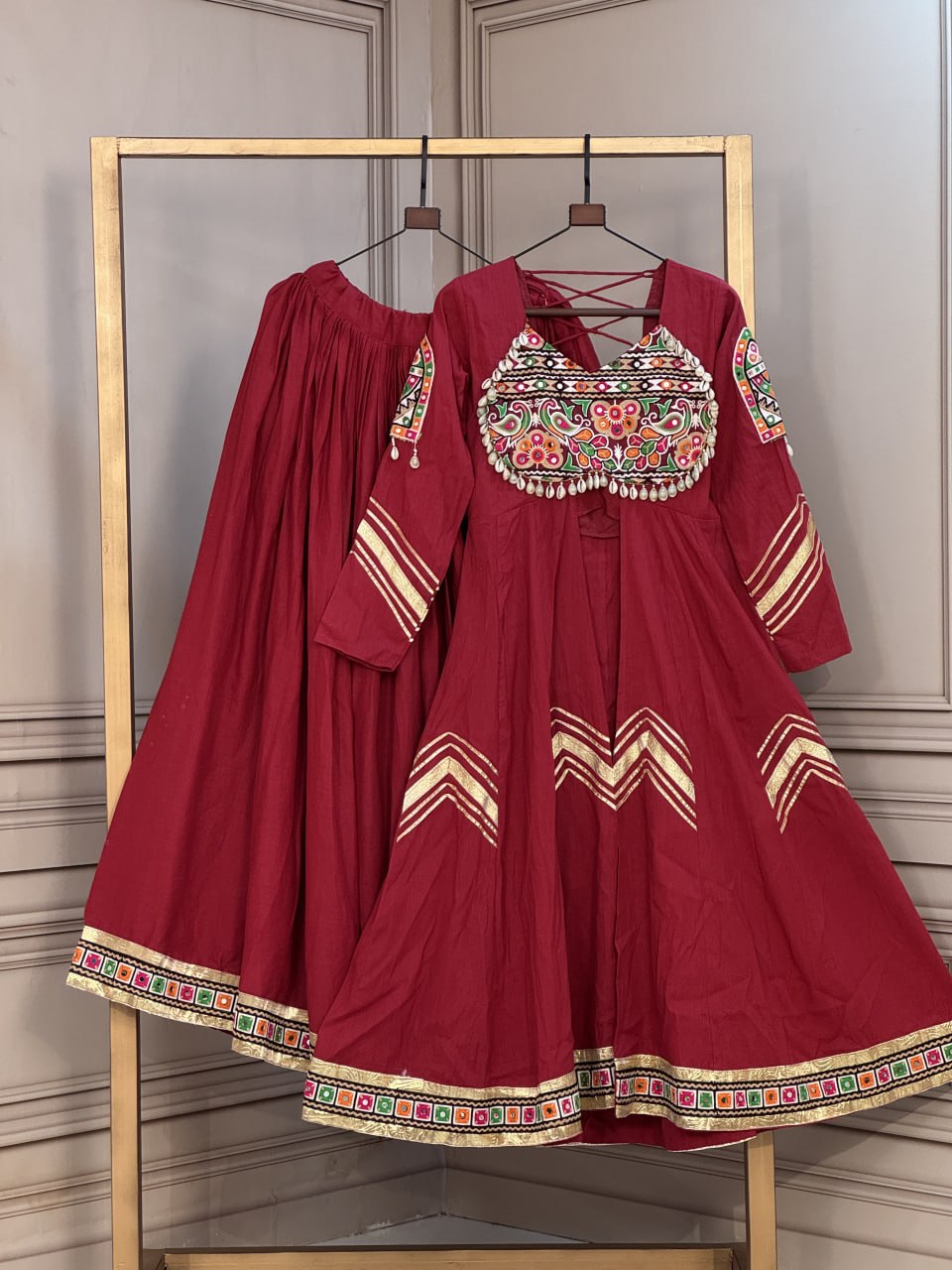 Maroon Crimson Red Kora Cotton Navratri Special Flared Lehenga Choli Set with Gujarati Gamthi Embroidery, Cowrie Shell Trims, Chevron Gota Patti & Long Flared Kedia Style Angrakha Top