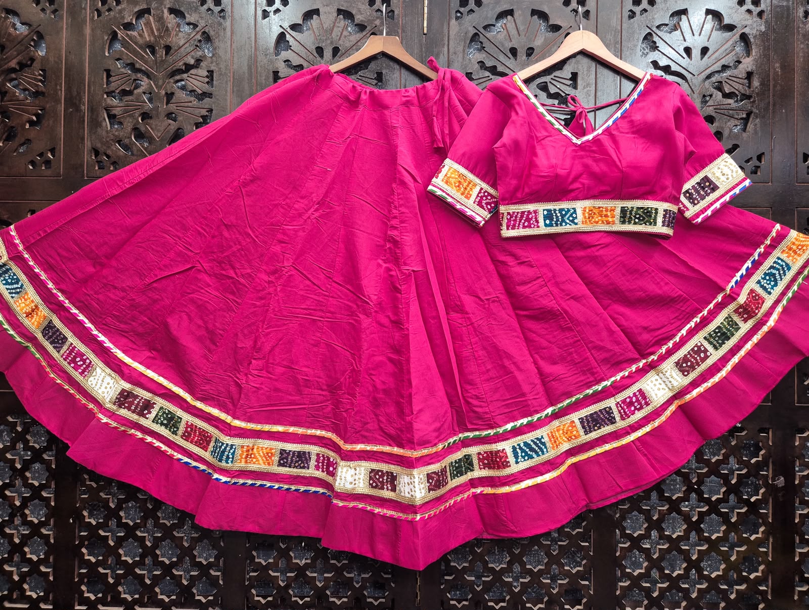 Flat-lay display of a Rani Pink Pure Cotton Navratri Kalidar Flared Lehenga Choli with Multi-Color Bandhani Patchwork Border and Gold Gota Patti Lace by The Beauty Queen