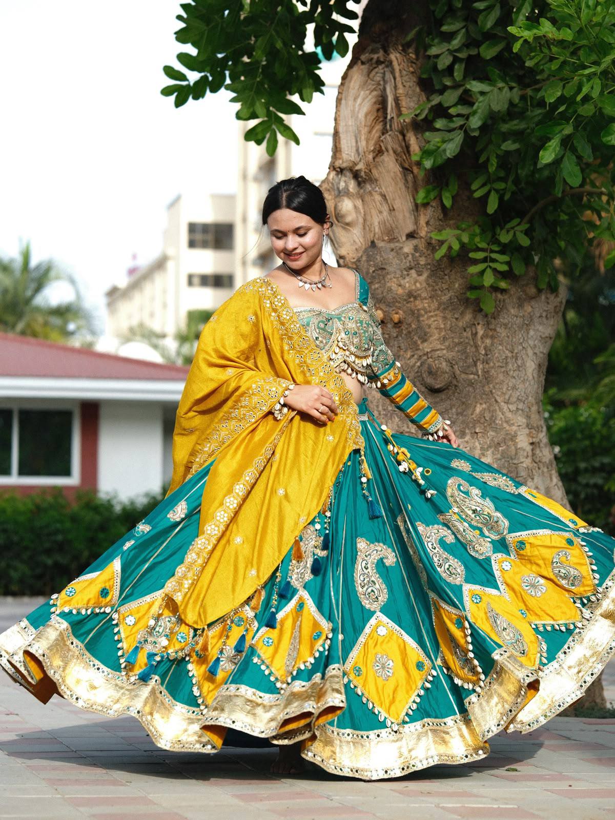 Model twirling in Teal Blue & Mustard Yellow Heavy Muslin Cotton Real Mirror Work With Handmade 8 Mtr Kodi Lace Navratri Lehenga Choli Set by The Beauty Queen