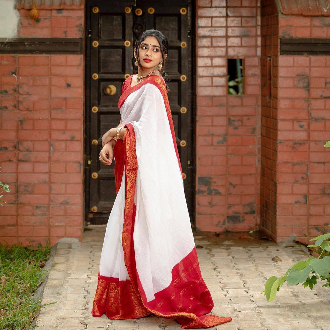 Image of An young and attractive Indian woman in white traditional sari and red  blouse and flowers is standing in a balcony for the celebration of  Onam/Pongal. Indian lifestyle.-PZ785858-Picxy